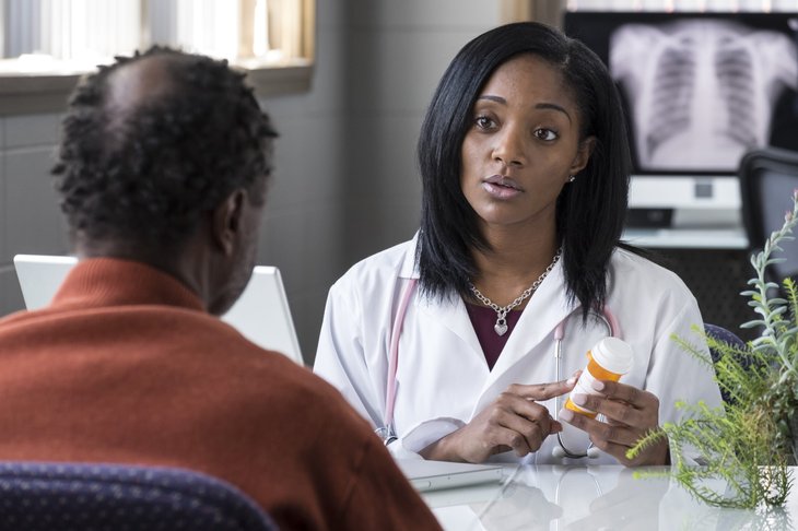 Une femme médecin noire prescrivant des pilules à un patient noir plus âgé