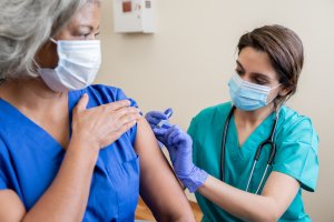 Une infirmière donne à un travailleur de la santé adulte senior le vaccin Covid-19