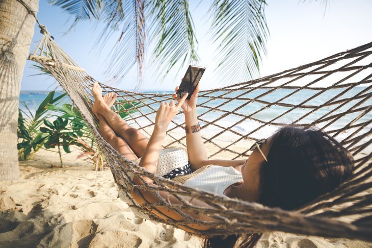 Femme à la plage en vacances avec son téléphone