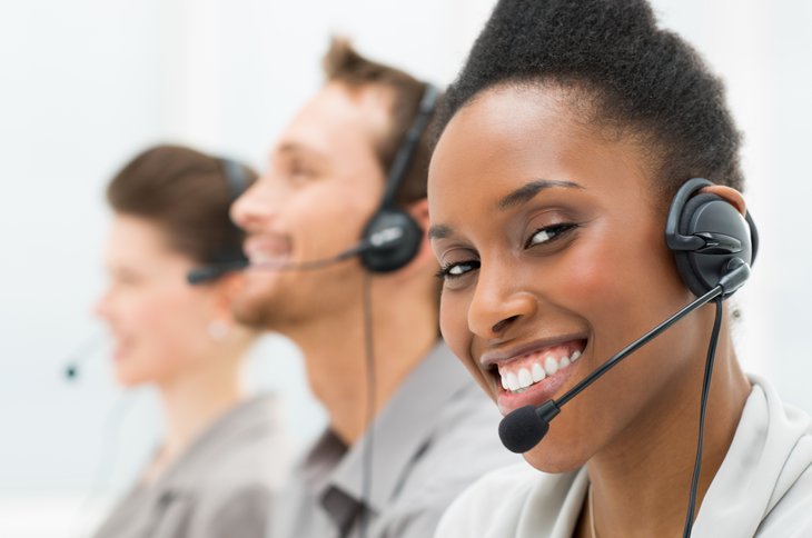 Gros plan de l'opérateur téléphonique afro-américain heureux avec ses collègues