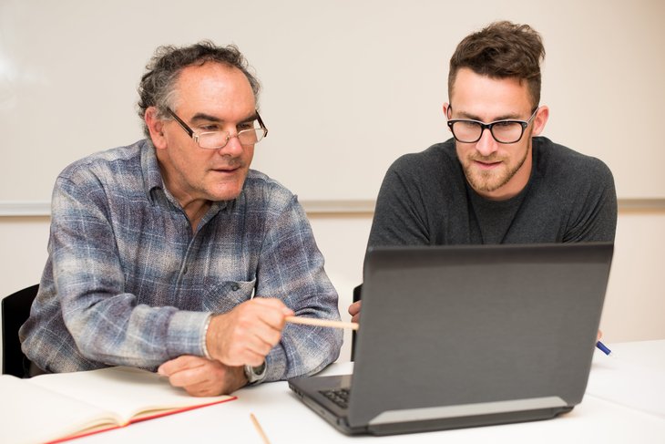 Professeur et assistant travaillant sur un ordinateur portable