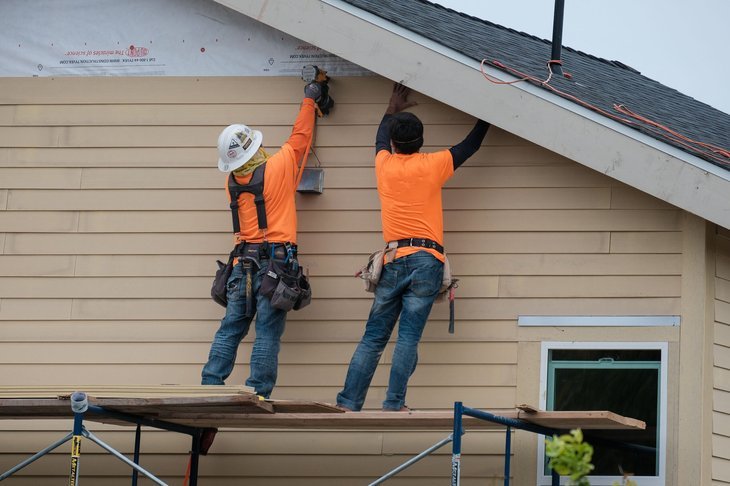 Travailleurs de la construction installant un revêtement en vinyle sur une maison à Los Angeles, Californie