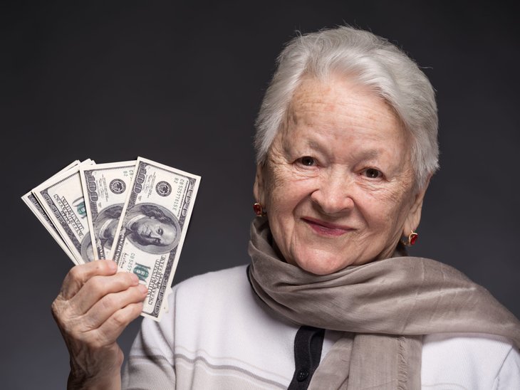 Femme âgée souriante tenant de l'argent