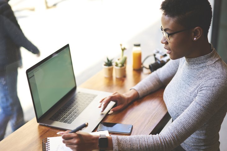 Une femme noire travaille à distance sur un ordinateur portable